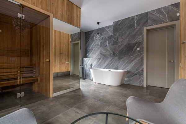 Luxurious bathroom with a snow-white bathtub against a marble wall in natural light Crystal chandeliers in the bathroom. Laconic design. Space for relaxation and pleasure. Bathroom window.