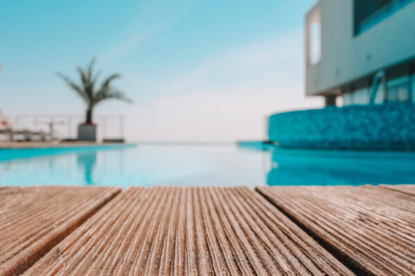 Empty wooden deck with swimming pool , Beautiful minimalist pool side view with clear blue sky . Vintage filter color apply Empty wooden deck with swimming pool , Beautiful minimalist pool side view with clear blue sky . Vintage filter color apply .